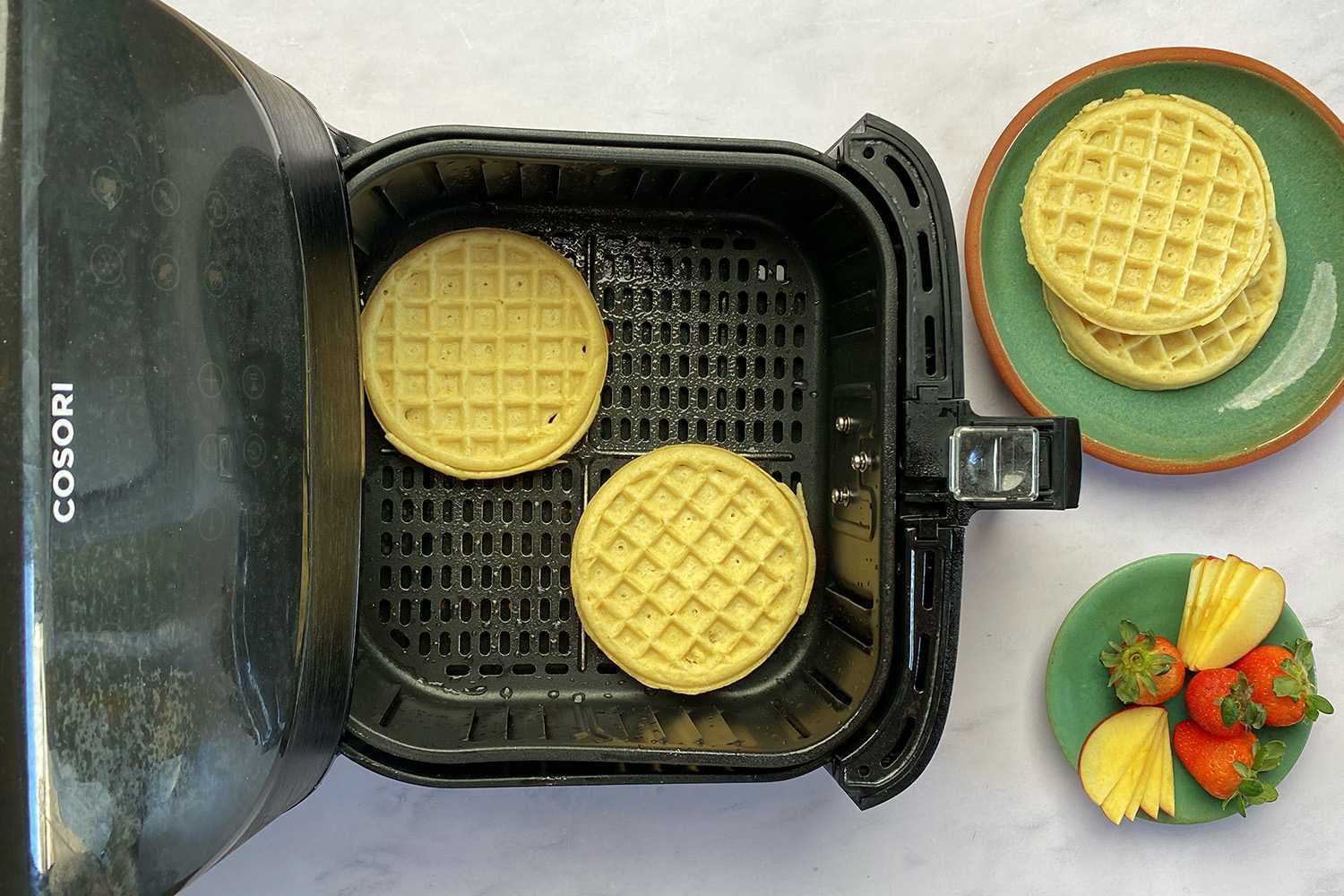 Frozen waffles placed into the air fryer basked prior to cooking.