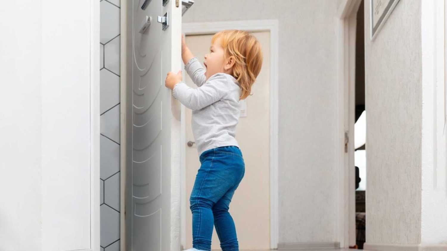 A little toddler opening the door. Protecting children from accidents. Low angle view.