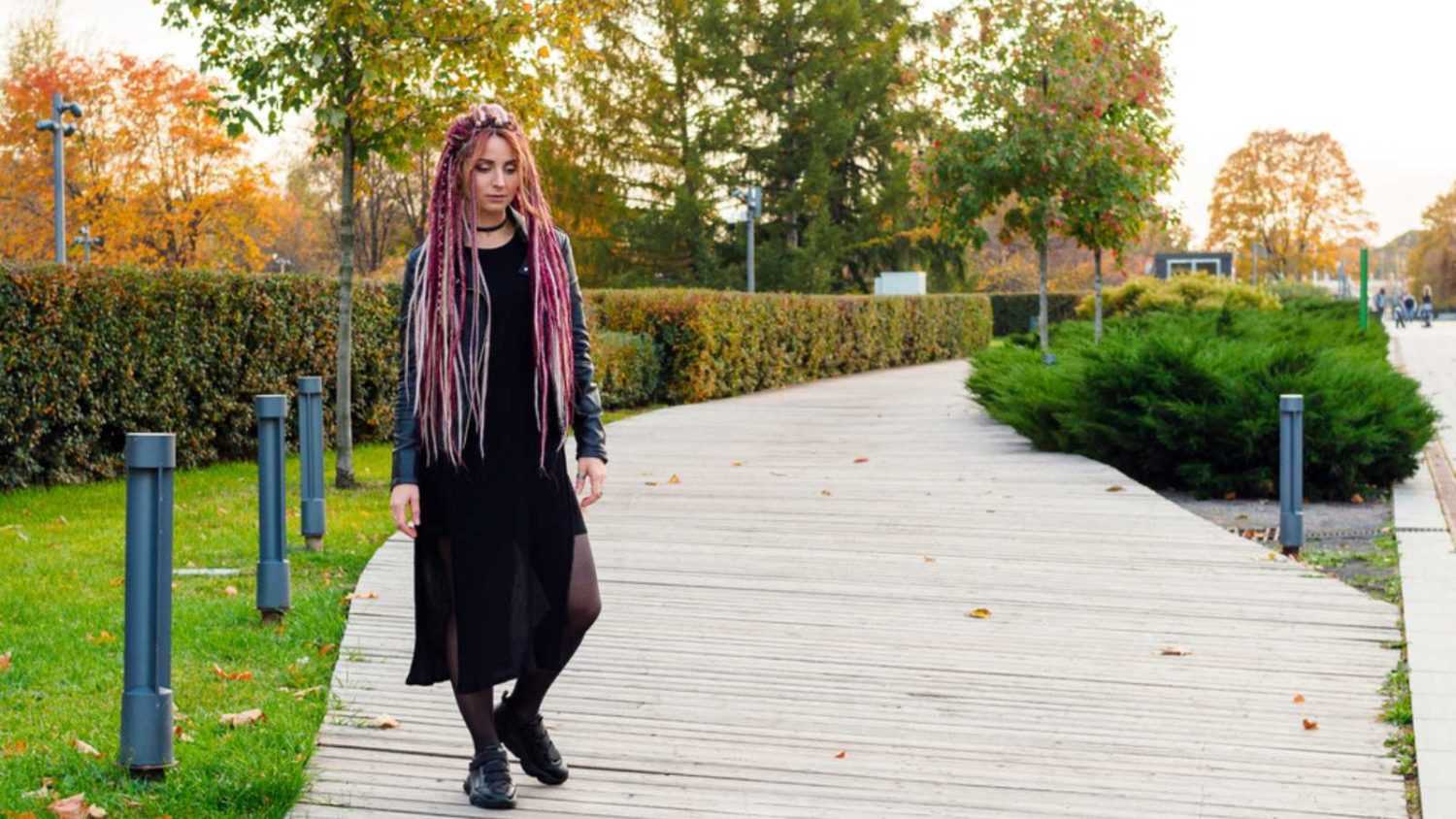 beautiful woman with long pink dreadlocks and pigtails walks in the park