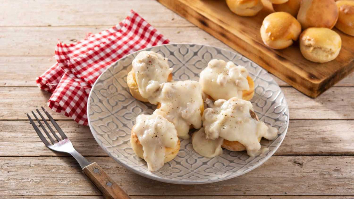 Traditional American biscuits and gravy for breakfast on wooden table