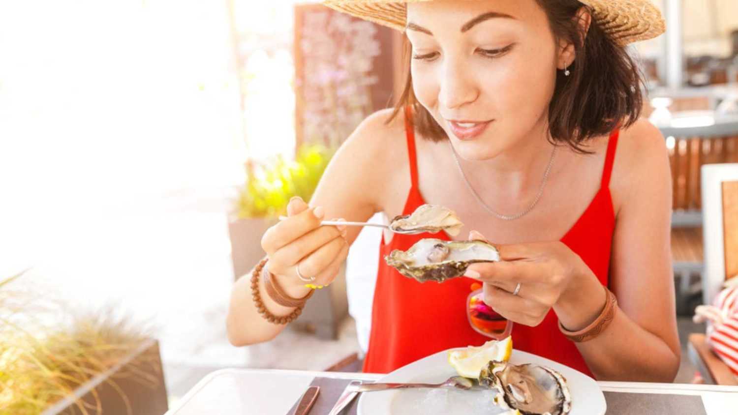 woman eating fresh oyster in seafood mediterranean restaurant