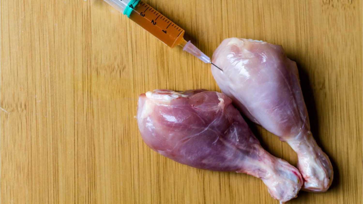 Injection syringe in raw chicken pieces, concept of injection of GMOs into the meat. selective focus. Copy space