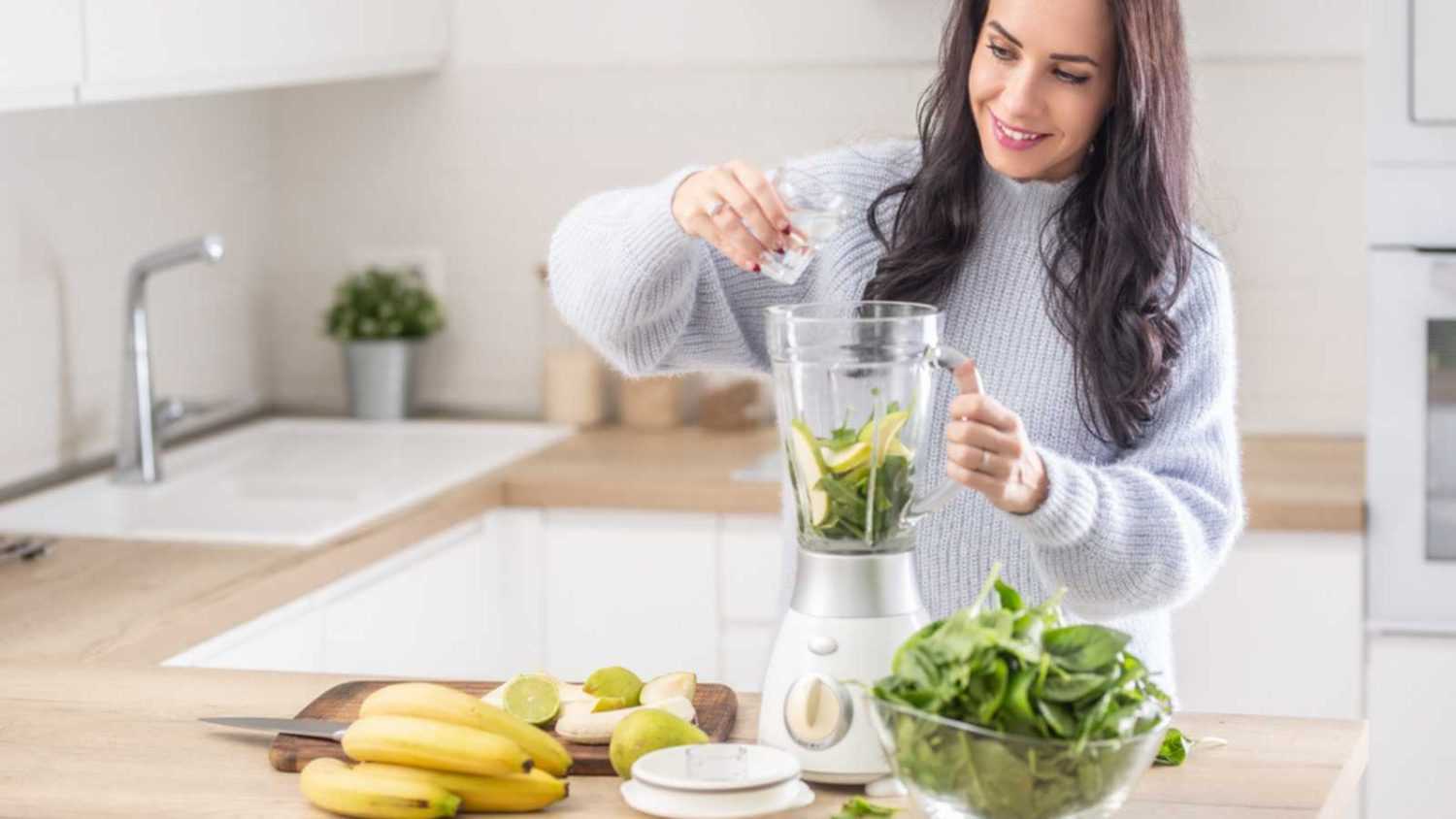 Woman making shake with leafy green and banana