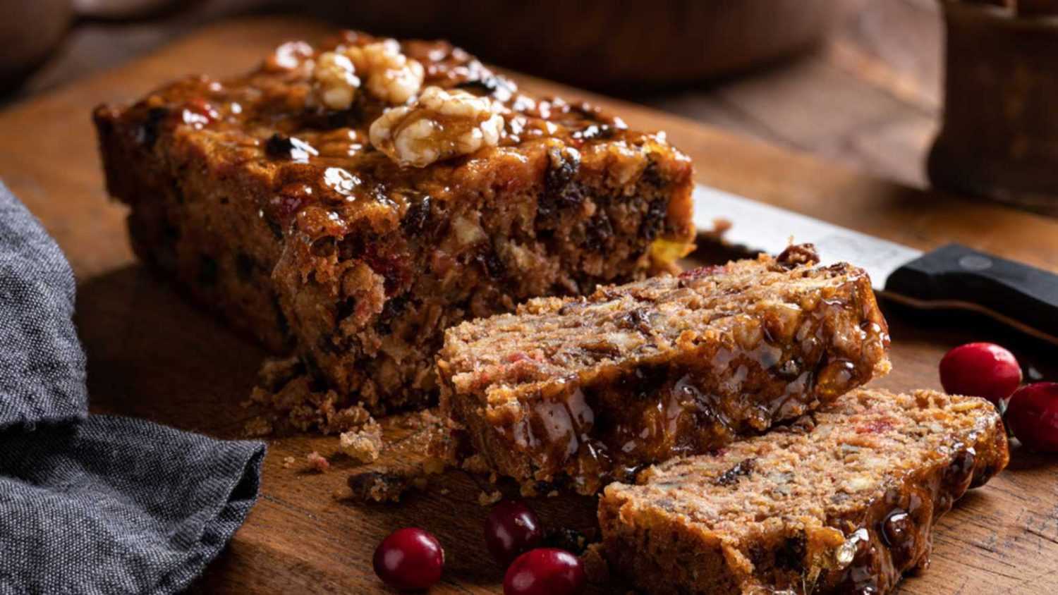 Fruitcake loaf sliced on a rustic wooden cutting board
