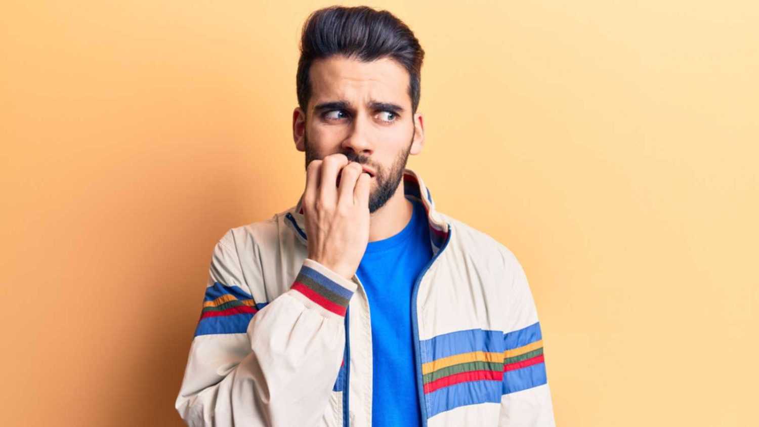 Young handsome man with beard wearing casual jacket looking stressed and nervous with hands on mouth biting nails. anxiety problem.