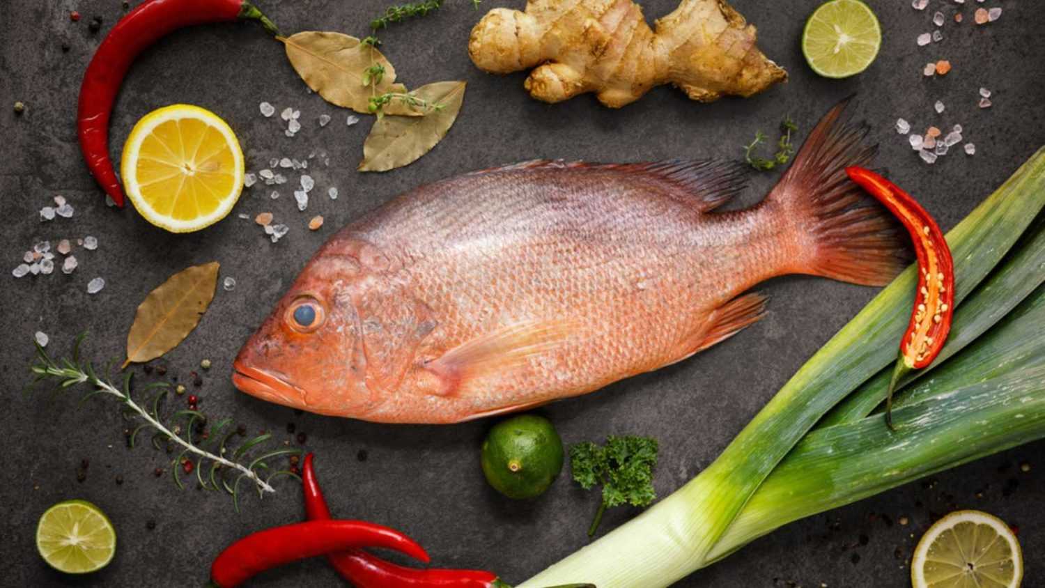 Fresh ingredients to cook fish, red snapper, leak, lime, lemon, parsley, chili pepper, ginger. Top view