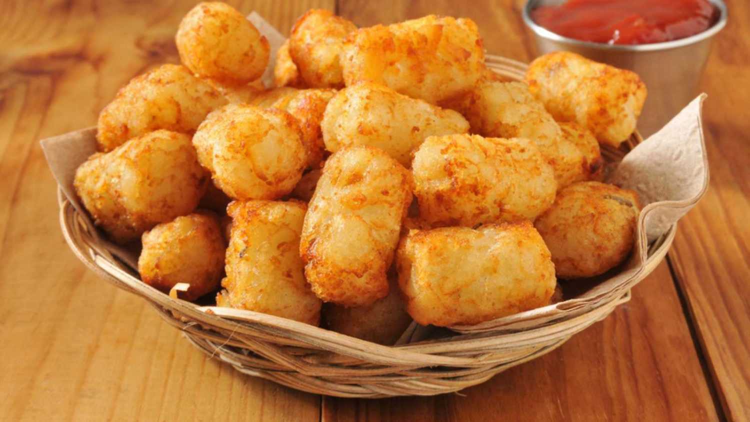 A basket of tater tots on a rustic wooden counter