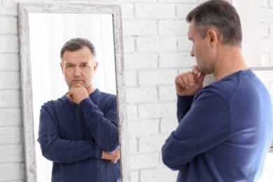 Man looking into mirror regretting