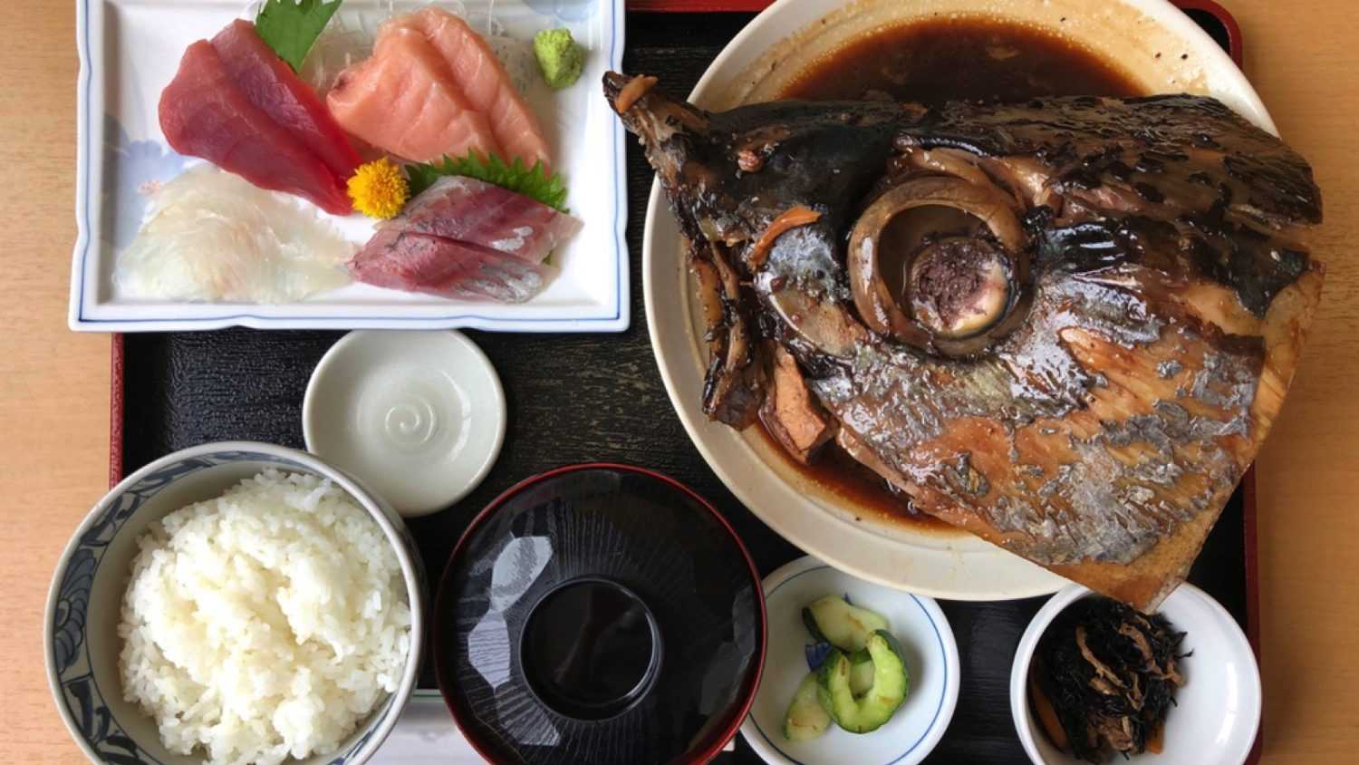 Japanese cuisine lunch set menu with simmered tuna head and assorted sashimi serve with rice, soup and pickles in tray. Simmered in the Japanese style called nitsuke.