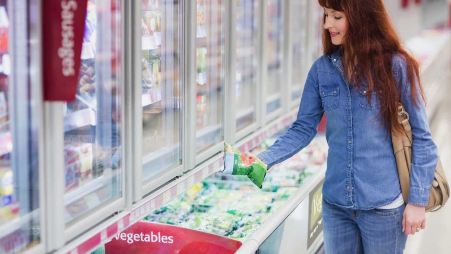 Woman buying frozen vegetables in shop