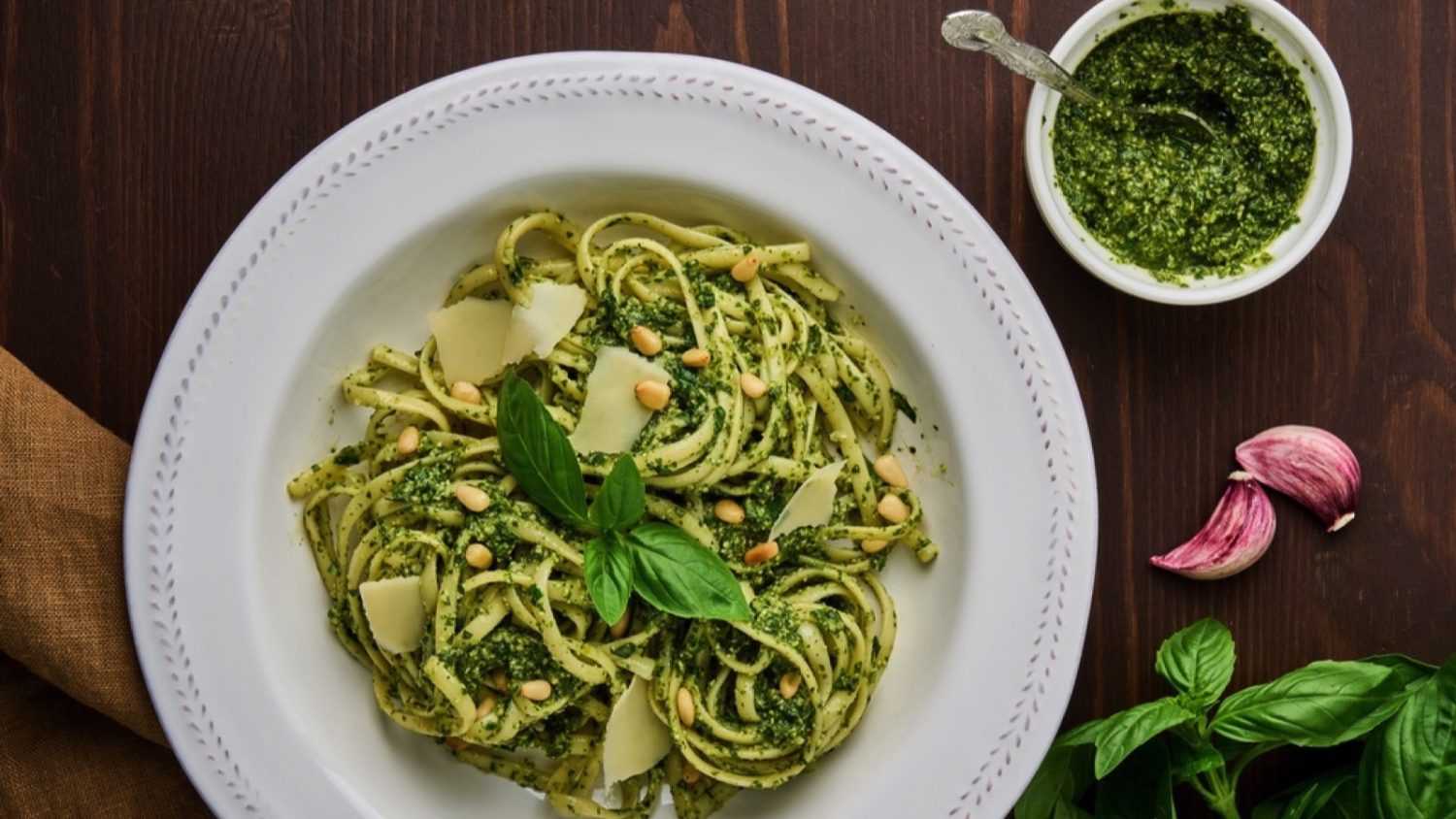 Classic italian pasta pesto with pine nuts, pound garlic, basil leaves, hard parmesan cheese and extra-virgin olive oil. Mediterranean pesto sauce and tagliatelle. Healthy homemade vegetarian