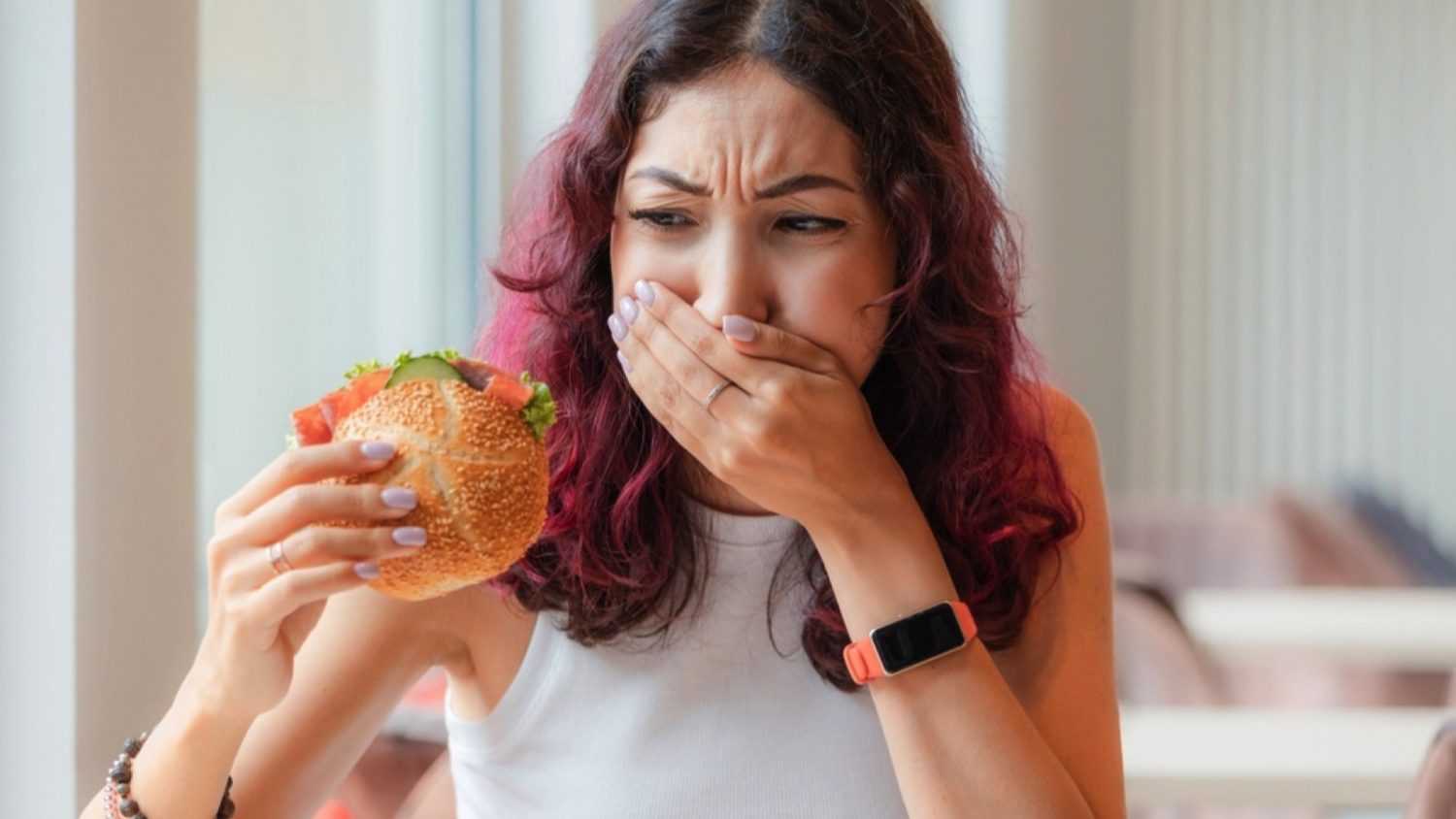 Woman eating burger closing mouth