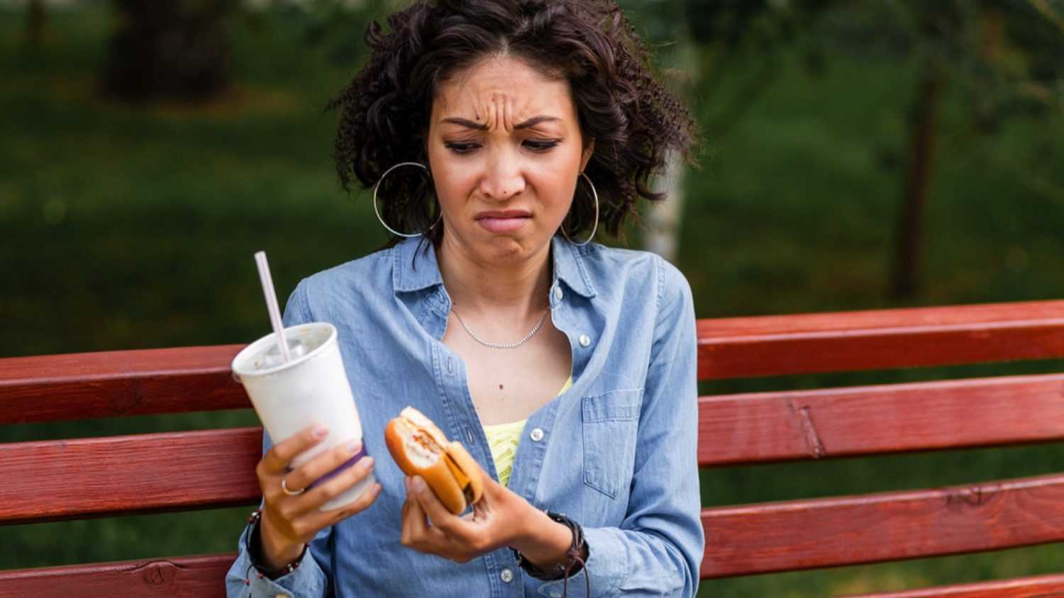 Woman tasting bad quality burger