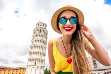 Young female traveler smiling near Pisa tower