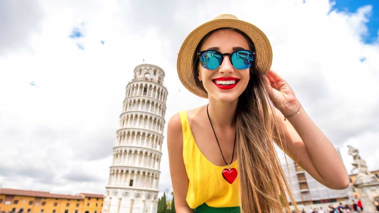 Young female traveler smiling near Pisa tower